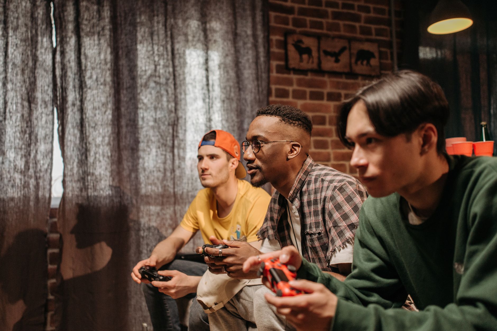 Three men focused on playing video games with controllers indoors. — Enjoy Secure Online Gaming and Daily Bonus Opportunities