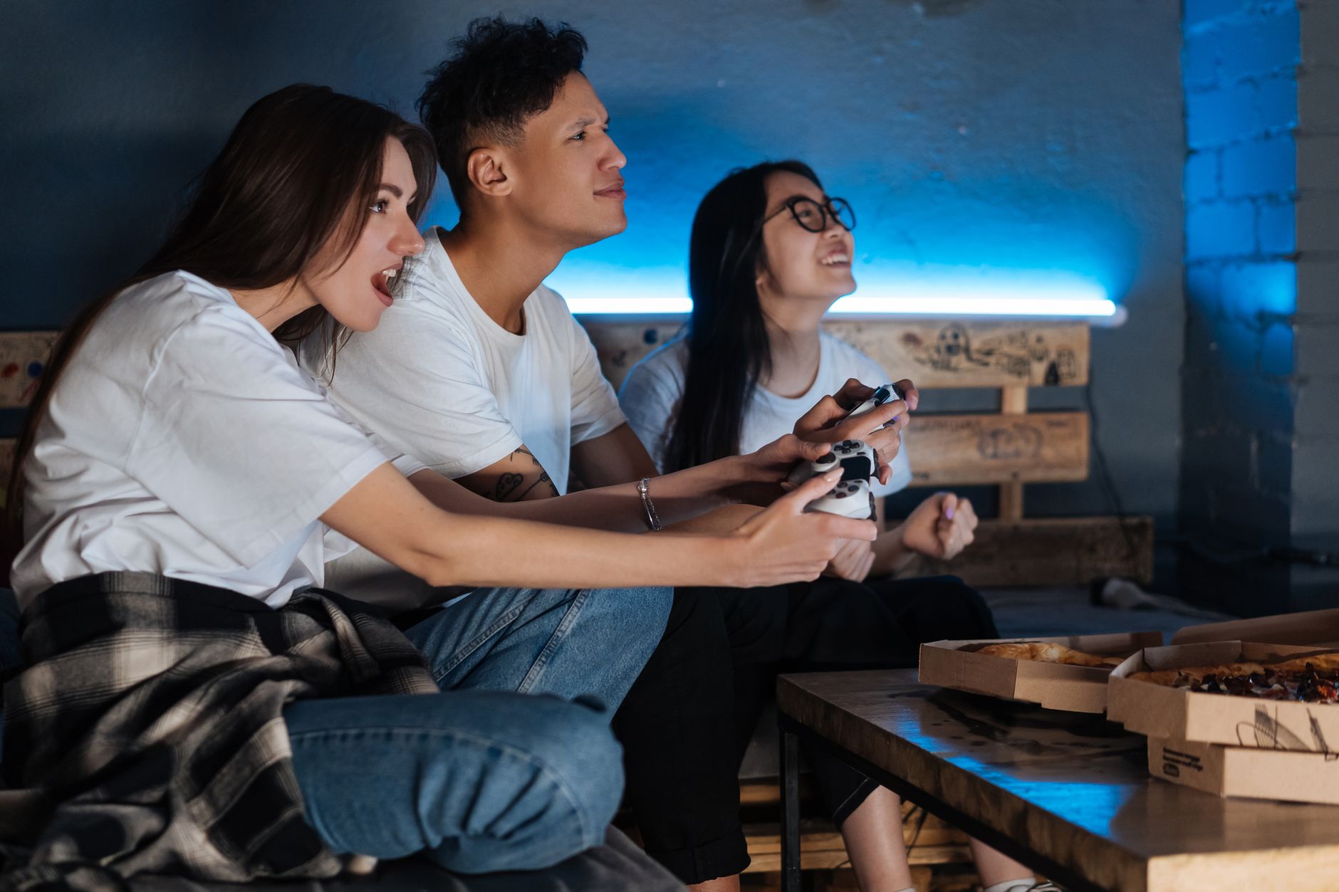 Three friends play video games together indoors, enjoying pizza and fun times. — Wzrost kasyn z Blikiem: Trendy w grach onlin